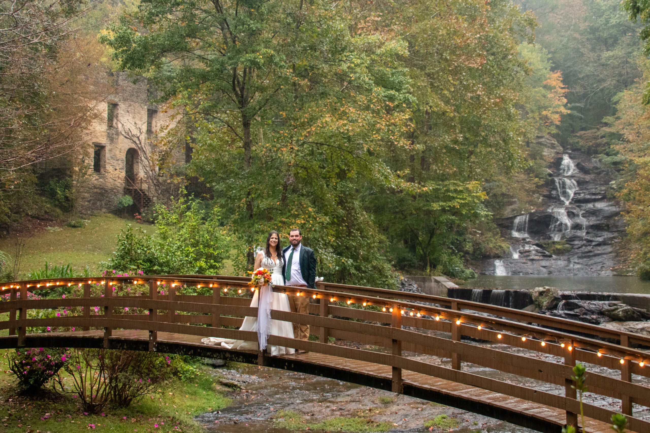 North Georgia wedding venue bride and groom pose for photos at a luxury outdoor wedding ceremony bridge with waterfall