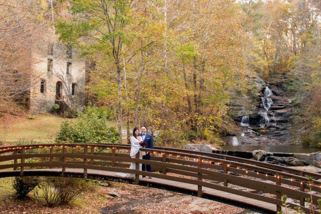 Atlanta area wedding venue by a waterfall, bride in luxury designer wedding dress pose at an outdoor wedding ceremony during fall near Atlanta Georgia