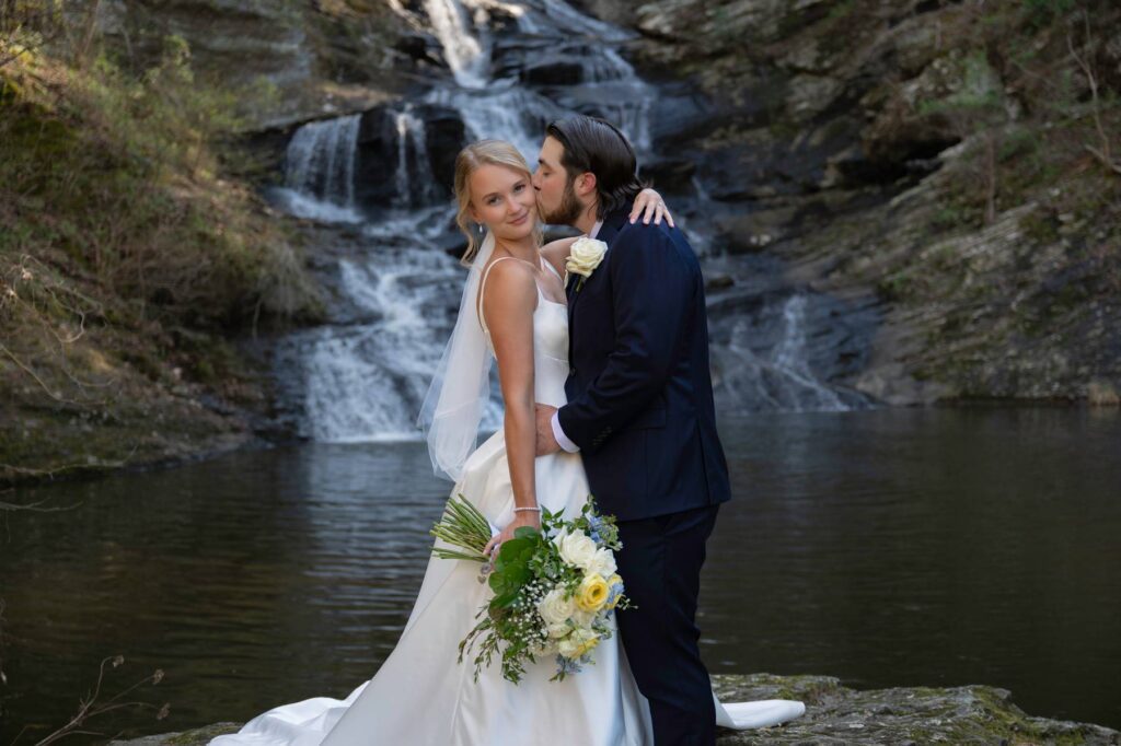 Bride and groom kissing in front of a waterfall at a beautiful wedding venue near Atlanta