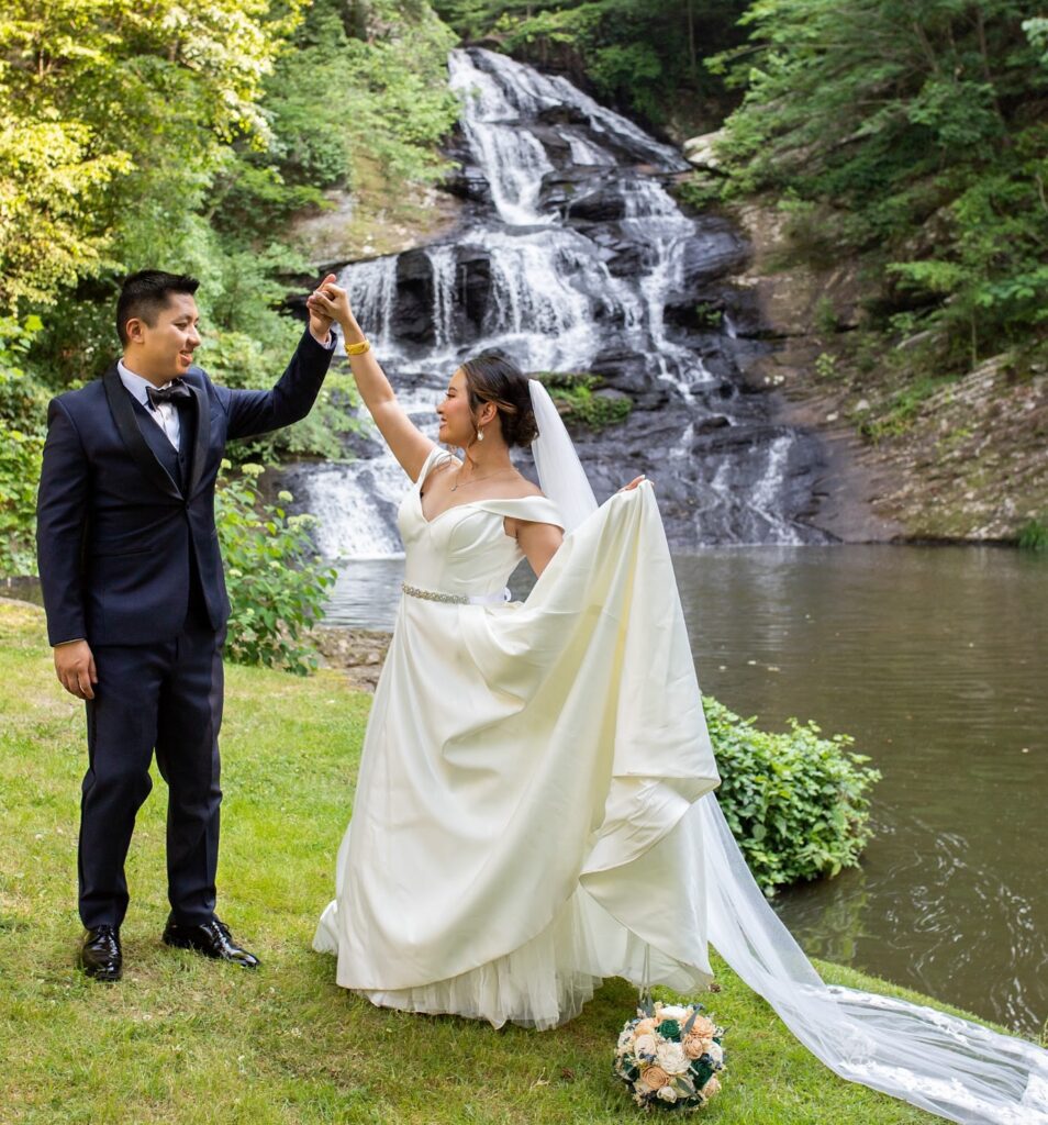 Bride and groom pose for wedding day photos by a wedding waterfall and outdoor ceremony at a fall wedding venue near Atlanta in North Georgia